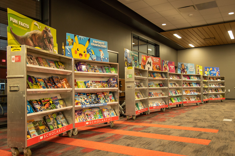 A row of book displays inside an event spaces, holding a variety of books for young and advancing readers.